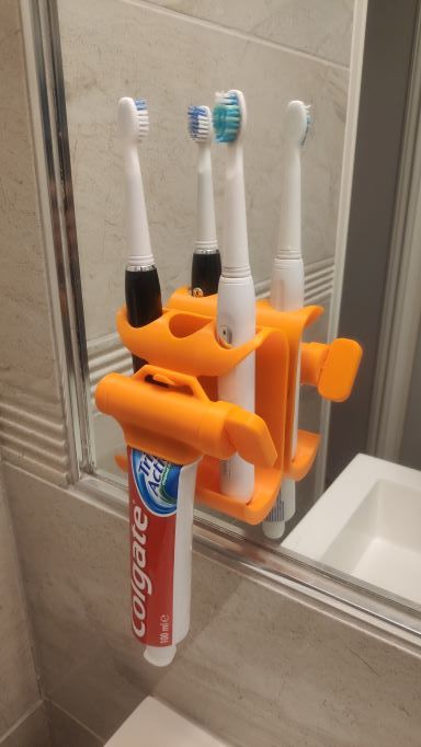 Soporte de pared y exprimidor de pasta para cepillo de dientes.