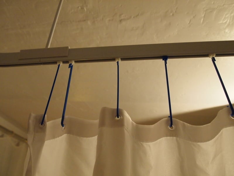 Gancho de longitud ajustable para cortina de ducha.